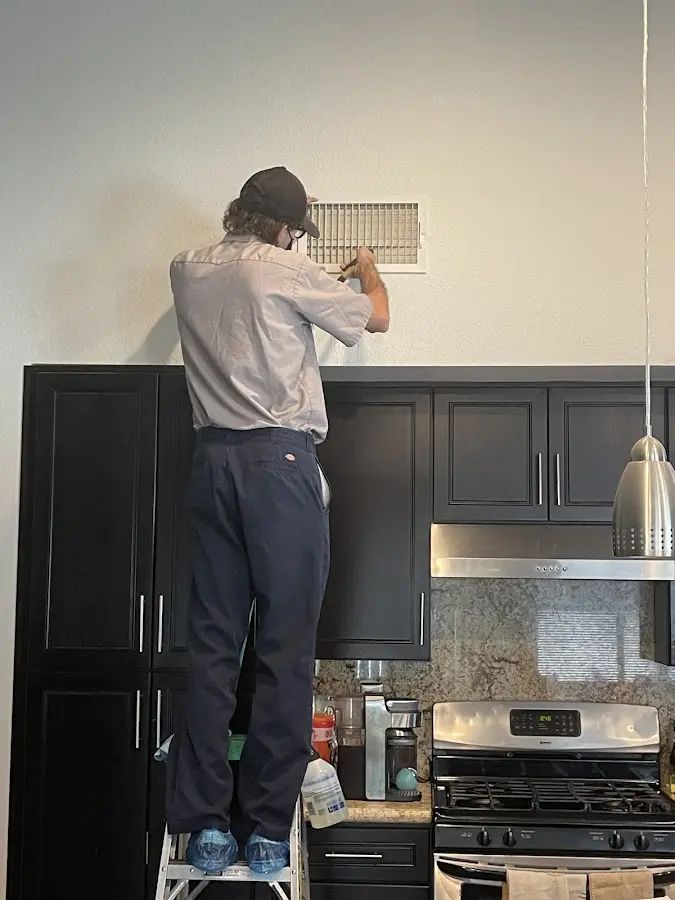 Technician inspecting an air vent during HVAC service in San Rafael